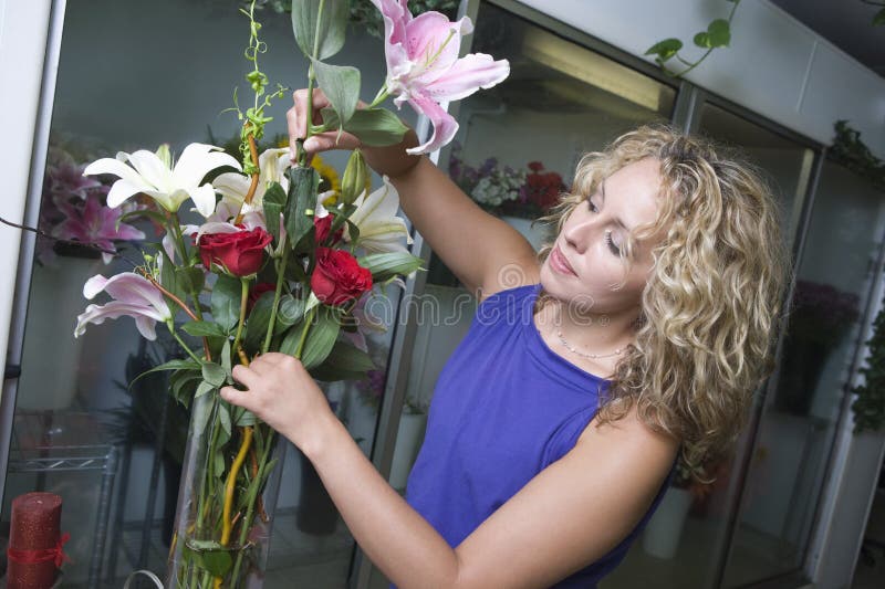 Young female florist arranging flowers in vase. Young female florist arranging flowers in vase