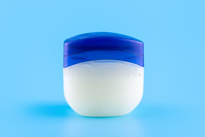 Vaseline or petroleum jelly in a clear jar on blue background with copy space for text. Skin care ointment