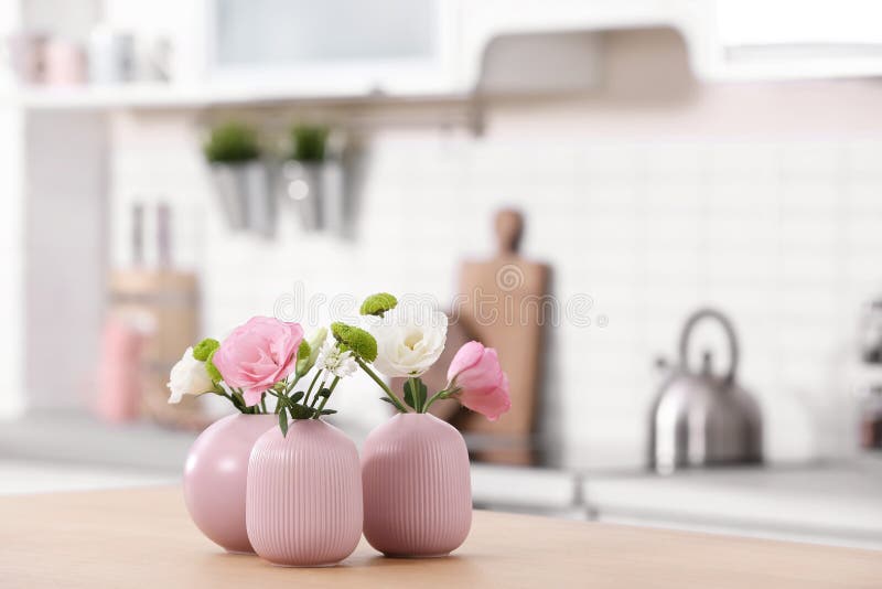 Vases with Beautiful Flowers on Table in Kitchen Interior. Stock