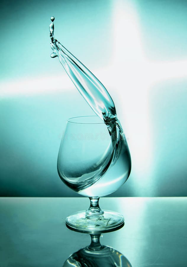 Vaso de agua con una onda en un fondo azul imágenes de archivo libres de regalías Vaso de agua con una onda en un fondo azul imágenes de archivo libres de regalías