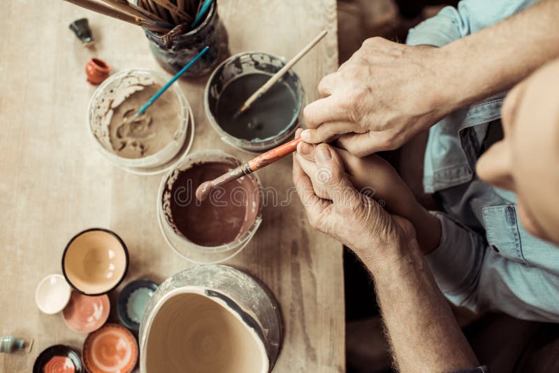 Vaso e nonni di argilla della pittura della ragazza che aiutano all'officina immagini stock Vaso e nonni di argilla della pittura della ragazza che aiutano all'officina immagini stock