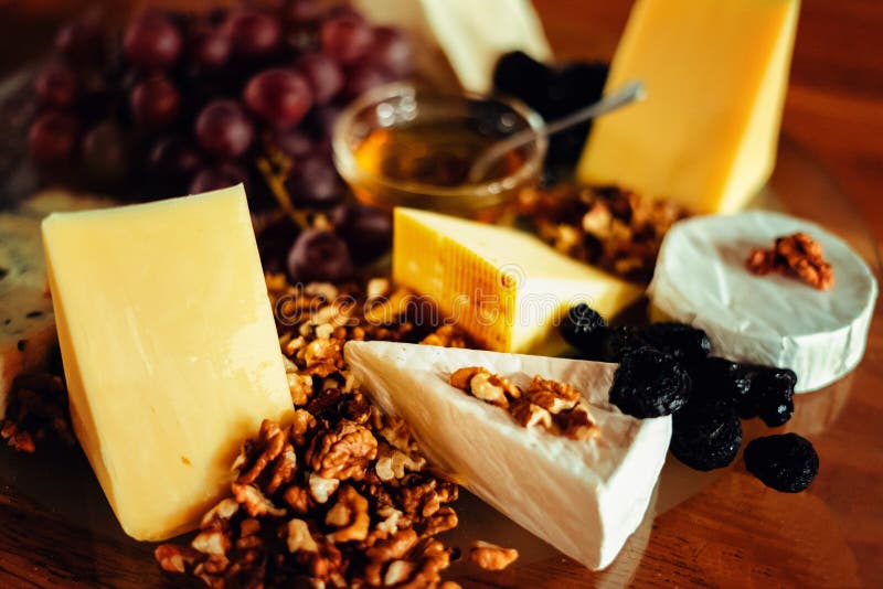 Vassoio del formaggio con differenti formaggi, uva, dadi, miele, brea fotografia stock