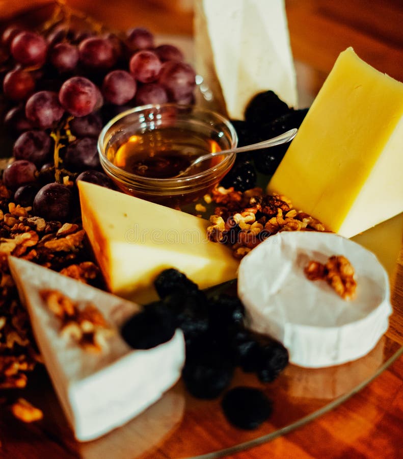 Vassoio del formaggio con differenti formaggi, uva, dadi, miele, brea fotografia stock libera da diritti