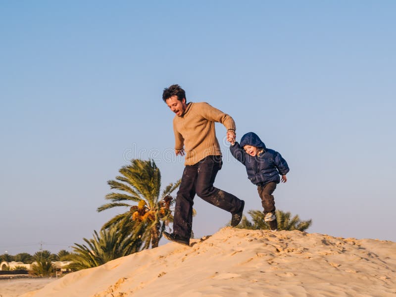 Vater lässt eine vorbei Düne des Sahara-Wüstenhändchenhaltens zu hallo laufen