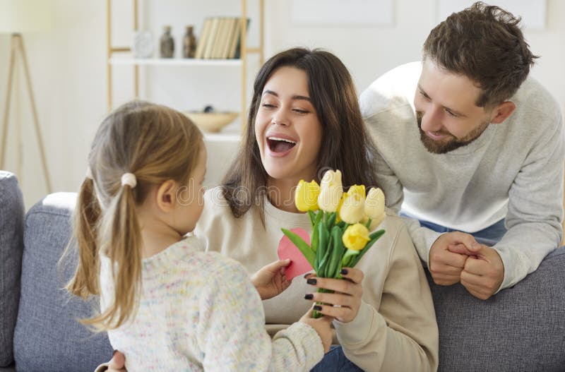 Vater mit Tochter gratulierte jungen glücklichen Mutter zu ihrem Urlaub zu Hause. lizenzfreie stockfotografie