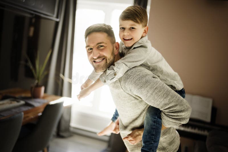 Vater oder Pate, der sich im Wohnzimmer auf seinem Rücken amüsiert stockbild