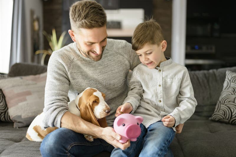 Vater oder Pate mit Basset Hund Spaß auf dem Wohnzimmer zu Hause pausen Geld auf Sparschwein lizenzfreies stockbild