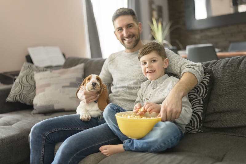 Vater oder Pate mit Basset Hund Spaß auf dem Wohnzimmer zu Hause sehen Film mit Popcorn lizenzfreies stockfoto