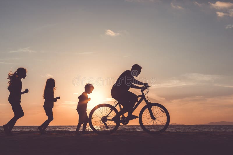 Vater und Kinder, die auf dem Strand zur Sonnenuntergangzeit spielen stockbild Vater und Kinder, die auf dem Strand zur Sonnenuntergangzeit spielen stockbild