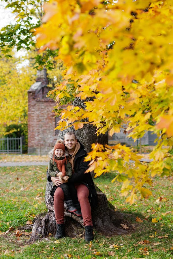 Vater und seine kleine Tochter im Herbstpark sitzen auf Baum
