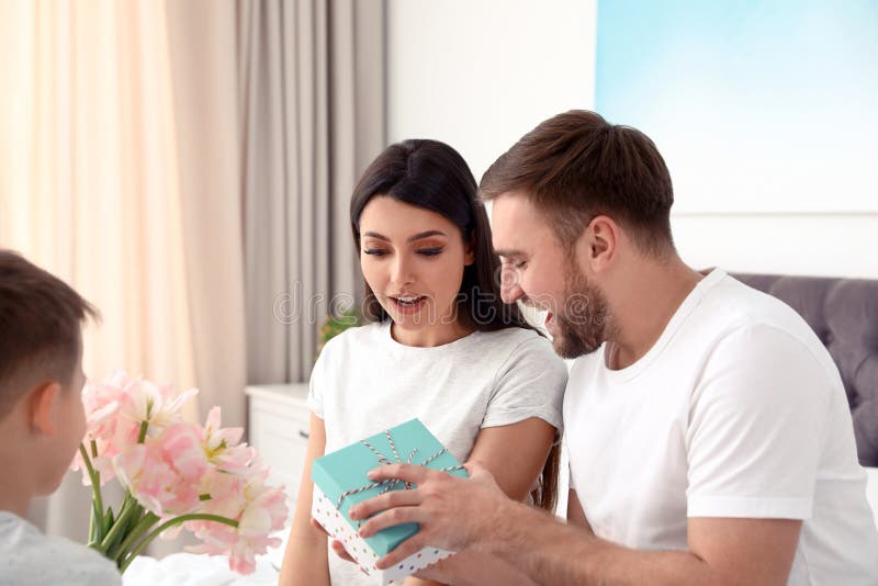 Father and son congratulating mom. Happy Mother`s Day. Father and son congratulating mom in bedroom.