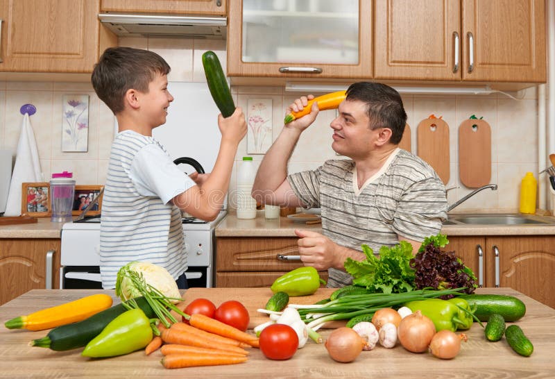 Vater und Sohn, die Spaß mit Gemüse im Hauptkücheninnenraum haben Mann und Kind Obst und Gemüse Gesundes Nahrungsmittelkonzept lizenzfreie stockfotos Vater und Sohn, die Spaß mit Gemüse im Hauptkücheninnenraum haben Mann und Kind Obst und Gemüse Gesundes Nahrungsmittelkonzept lizenzfreie stockfotos