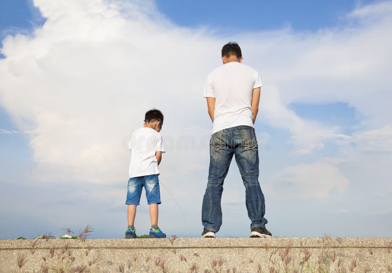 Vater und Sohn, die zusammen auf einer Steinplattform und einem Pipi stehen stockfotografie Vater und Sohn, die zusammen auf einer Steinplattform und einem Pipi stehen stockfotografie