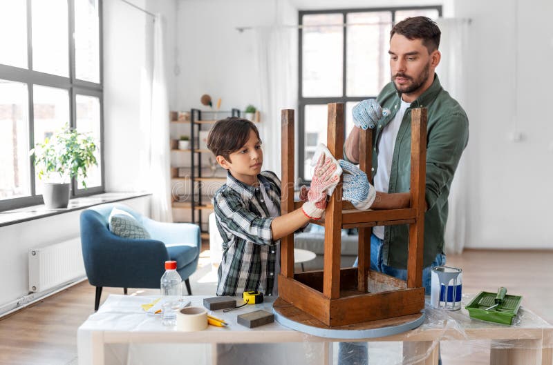 renovation, diy and home improvement concept - father and son degreasing old round wooden table surface with tissue. renovation, diy and home improvement concept - father and son degreasing old round wooden table surface with tissue