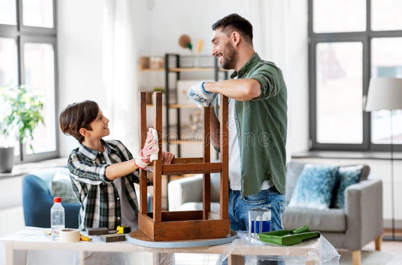 renovation, diy and home improvement concept - happy smiling father and son degreasing old round wooden table surface with tissue. renovation, diy and home improvement concept - happy smiling father and son degreasing old round wooden table surface with tissue