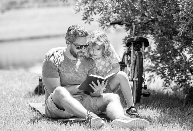 Vater und Sohn schaffen literarische Abenteuer in der Natur. Kinderlesezeit. Tradition für Vater und Sohn. Vater und Sohn stockbild