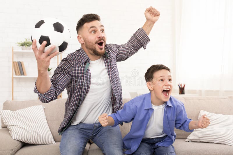Vater- und Sohnfu?ballfans, die mit Fu?ballball zujubeln lizenzfreie stockfotos Vater- und Sohnfu?ballfans, die mit Fu?ballball zujubeln lizenzfreie stockfotos
