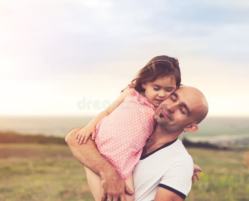 Vater und Tochter, die auf Sommersonnenuntergang umarmen stockbild Vater und Tochter, die auf Sommersonnenuntergang umarmen stockbild