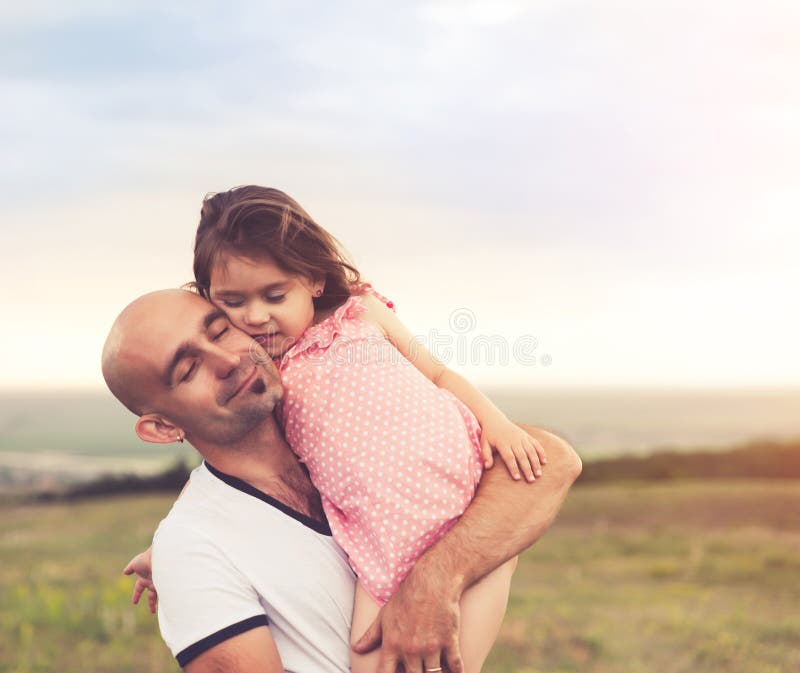 Vater und Tochter, die auf Sommersonnenuntergang umarmen lizenzfreies stockfoto Vater und Tochter, die auf Sommersonnenuntergang umarmen lizenzfreies stockfoto