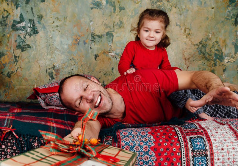 Vater und Tochter kämpfen für ein Geschenk auf dem Bett Ein Mädchen, das einen Erwachsenen reitet, versucht, ein Geschenk zu nehm stockfotos Vater und Tochter kämpfen für ein Geschenk auf dem Bett Ein Mädchen, das einen Erwachsenen reitet, versucht, ein Geschenk zu nehm stockfotos