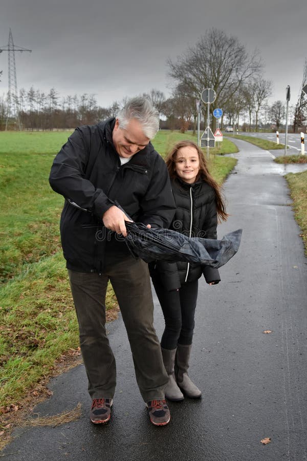 Vater und Tochter mit defektem Regenschirm stockfoto Vater und Tochter mit defektem Regenschirm stockfoto