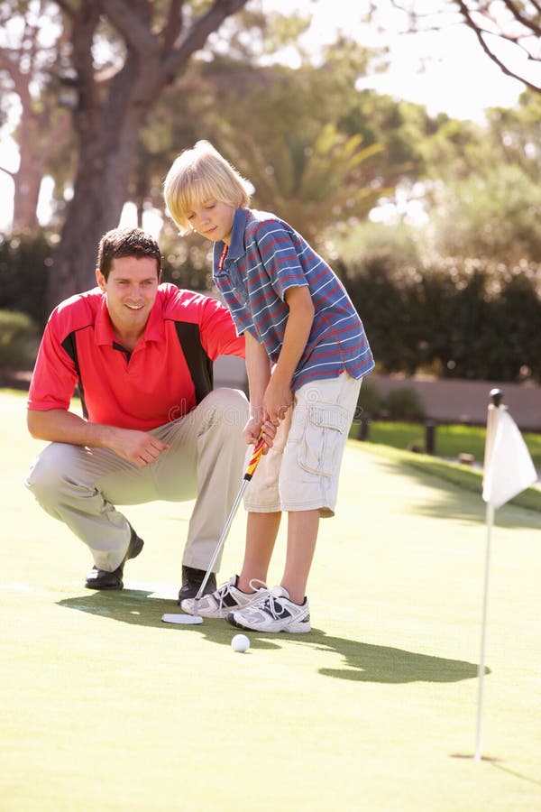 Vater-unterrichtender Sohn, zum des Golfs zu spielen stockfotografie Vater-unterrichtender Sohn, zum des Golfs zu spielen stockfotografie