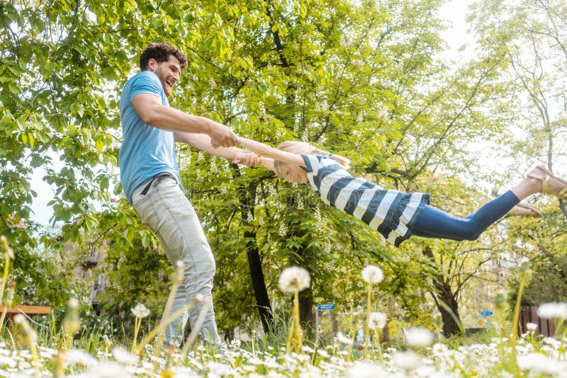 Vati, der mit seiner Tochter im Gras spielt. Vati, der mit seiner Tochter im Gras herum wirft sie spielt