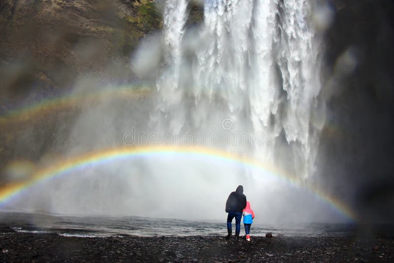 Vati und Kind unter dem Regenbogen am Fuß schweren Wasserfalls Skogafoss in Island lizenzfreies stockfoto Vati und Kind unter dem Regenbogen am Fuß schweren Wasserfalls Skogafoss in Island lizenzfreies stockfoto