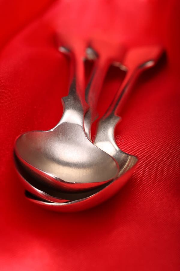 Old silver spoons on a decadent red silk tablecloth. Old silver spoons on a decadent red silk tablecloth