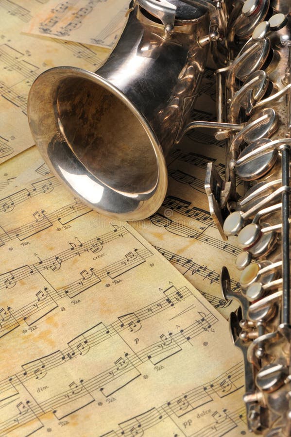 Old saxophone and notes. The Musical instrument laying on notes with classical music of the beginning of 17 centuries. Old saxophone and notes. The Musical instrument laying on notes with classical music of the beginning of 17 centuries