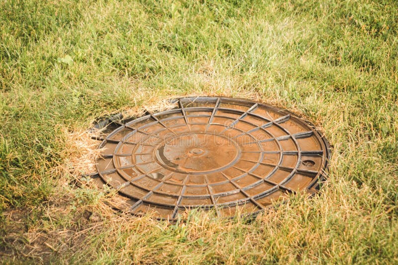 Vecchia botola rotonda arrugginita di fognatura con il fondamento fotografia stock libera da diritti Vecchia botola rotonda arrugginita di fognatura con il fondamento fotografia stock libera da diritti
