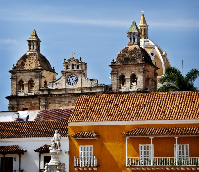 Colorful colonial architecture of Customs Square (Plaza de la Aduana) , formerly Colon Square, in Cartagena, Columbia, South America, with a statue of Christopher Columbus in the foreground, and the church towers and the church dome in the background. Colorful colonial architecture of Customs Square (Plaza de la Aduana) , formerly Colon Square, in Cartagena, Columbia, South America, with a statue of Christopher Columbus in the foreground, and the church towers and the church dome in the background.