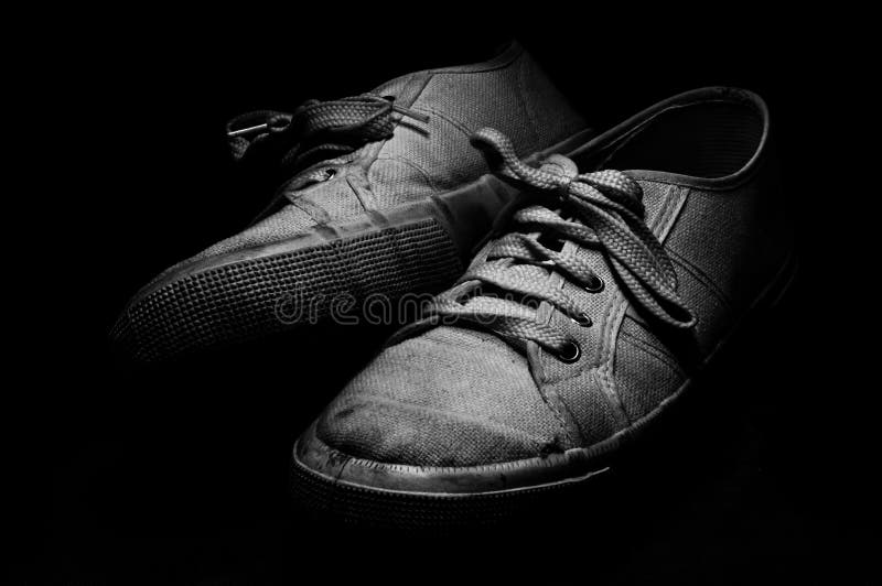 Vecchie scarpe di tennis su fondo nero fotografia stock libera da diritti Vecchie scarpe di tennis su fondo nero fotografia stock libera da diritti