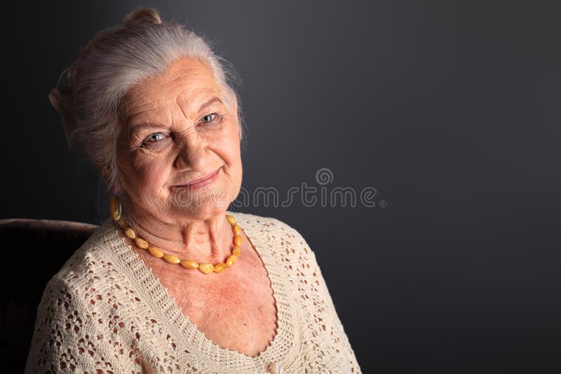 Portrait of a smiling senior woman. Studio shot over grey background. Portrait of a smiling senior woman. Studio shot over grey background.