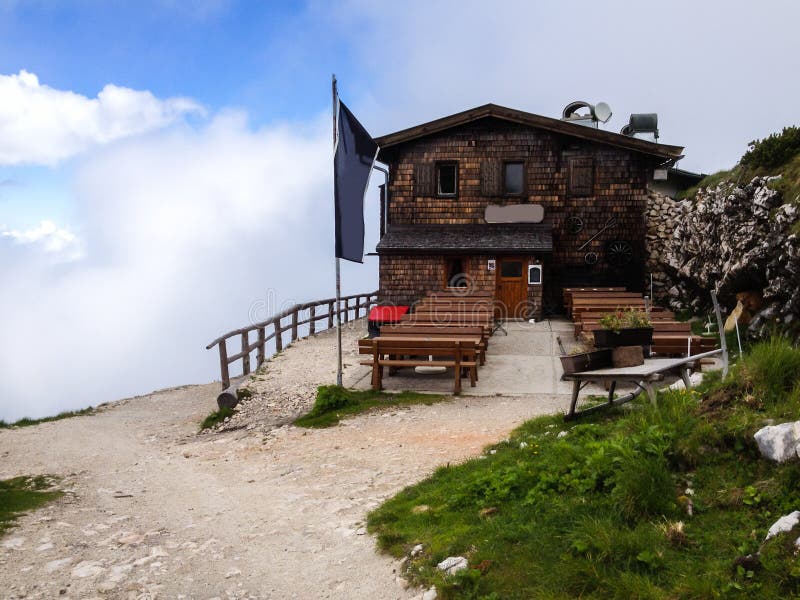 Vecchio cottage rustico tradizionale del chalet sui turisti di benvenuto della cima della montagna da rinfrescare dopo l'escursio immagini stock Vecchio cottage rustico tradizionale del chalet sui turisti di benvenuto della cima della montagna da rinfrescare dopo l'escursio immagini stock