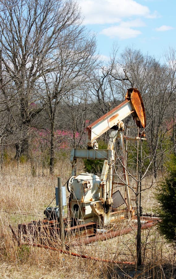 Vecchio pumpjack arrugginito del pozzo di gas dell'olio dietro il recinto del filo spinato fotografia stock Vecchio pumpjack arrugginito del pozzo di gas dell'olio dietro il recinto del filo spinato fotografia stock