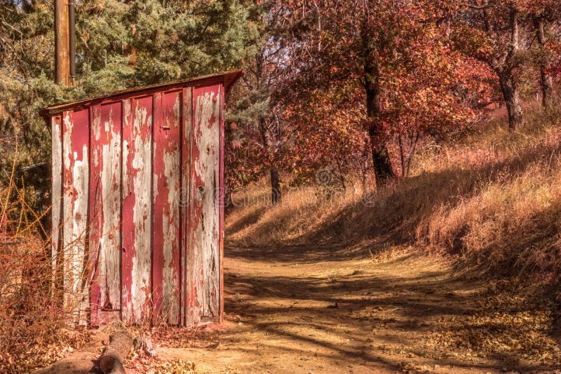 Vecchio, sbucciando pittura rossa su piccolo, legno fuori che costruisce sul percorso rurale fotografia stock Vecchio, sbucciando pittura rossa su piccolo, legno fuori che costruisce sul percorso rurale fotografia stock