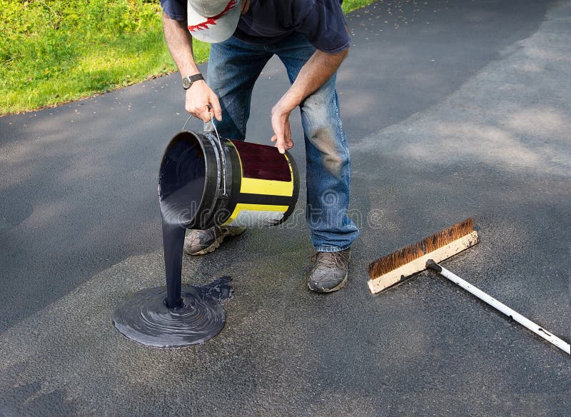 Do it yourself home maintenance. Driveway resealing repair. Pouring asphalt onto driveway from a bucket. Do it yourself home maintenance. Driveway resealing repair. Pouring asphalt onto driveway from a bucket