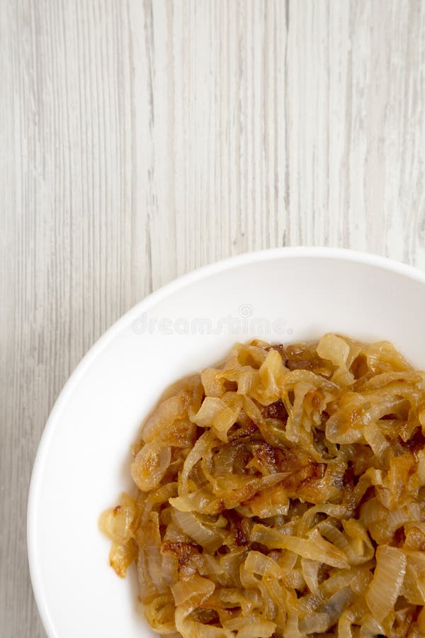 Vedere aeriană, ceapă caramelizată de casă pe o placă albă pe o masă albă din lemn. cheltuieli de regie fixe de deasupra. copiere royalty free stock image