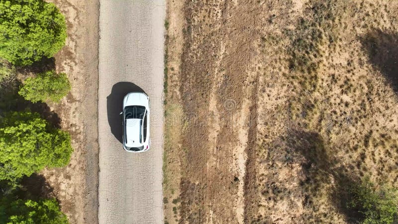 Vedere aeriană de răsturnare în urma unui autoturism alb care conduce de-a lungul unui drum rural în stare precară stock video