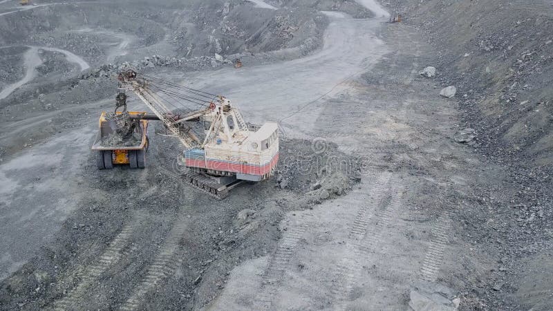 Vedere de sus a excavatorului în groapă deschisă. excavator adoarme moloz în coșul de gunoi al carierei în aer liber în extracția stock photo