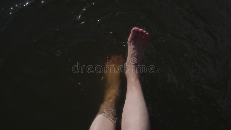 Vedere de sus picioare de sex feminin stropit în apă de râu într-o zi însorită de vară stock footage