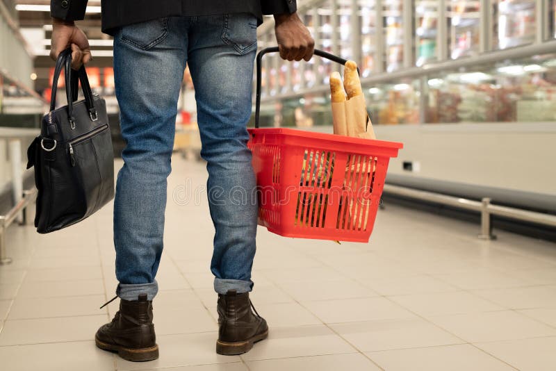 Vedere din spate a părții inferioare a tânărului cu coșul roșu care se deplasează între afișaje stock images