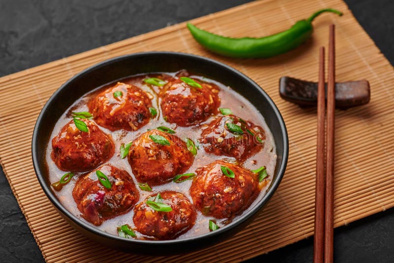 Veg Manchurian Gravy Balls in black bowl in dark slate table top. Vegetarian Manchurian is indian chinese cuisine dish