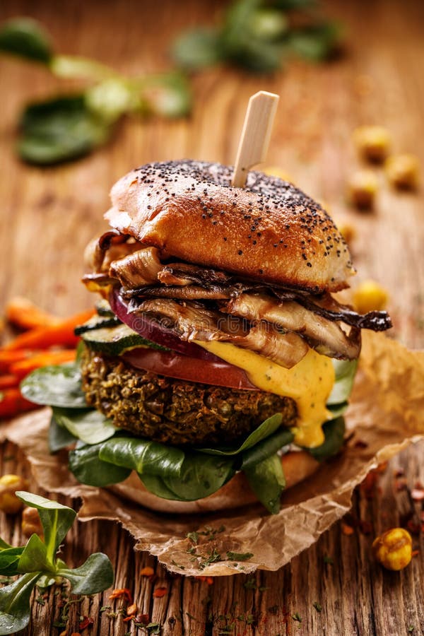 Vegan burger, green peas burger, homemade burger with green peas cutlet, grilled mushrooms, tomato, red onion, lamb`s lettuce, and royalty free stock photos Vegan burger, green peas burger, homemade burger with green peas cutlet, grilled mushrooms, tomato, red onion, lamb`s lettuce, and royalty free stock photos