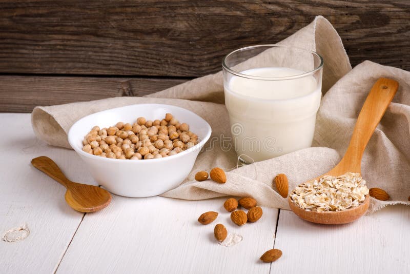 Vegan non dairy milk in glass and milk alternatives ingredients like a nut, almond, soy, oat on wooden table with kitchen towel. stock images Vegan non dairy milk in glass and milk alternatives ingredients like a nut, almond, soy, oat on wooden table with kitchen towel. stock images
