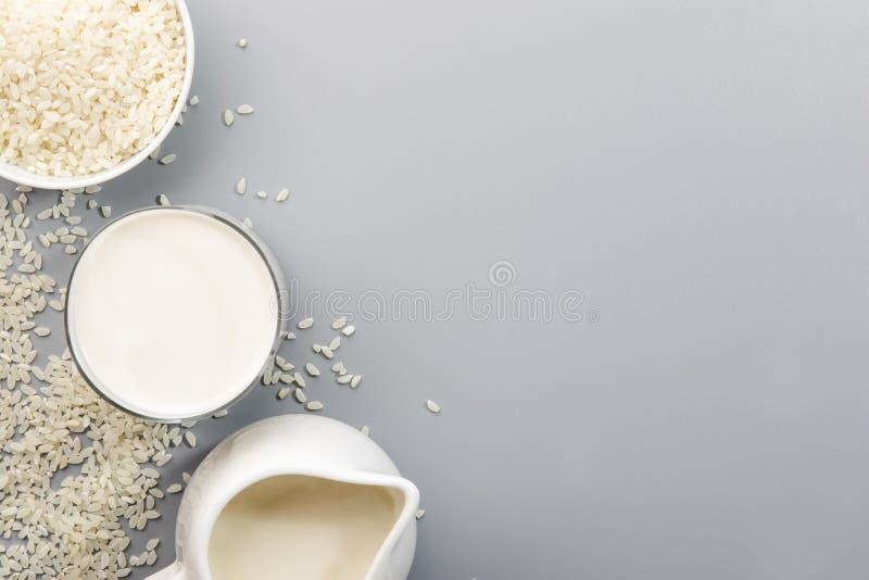 Vegan Rice Milk with Rice Grains on Gray Background. Copy Space, Top