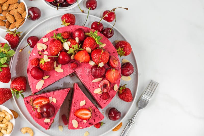 Vegan strawberry and cherry cheesecake with fresh berries and nuts and two slices of cake in a plate. top view. Healthy vegan dessert food stock images