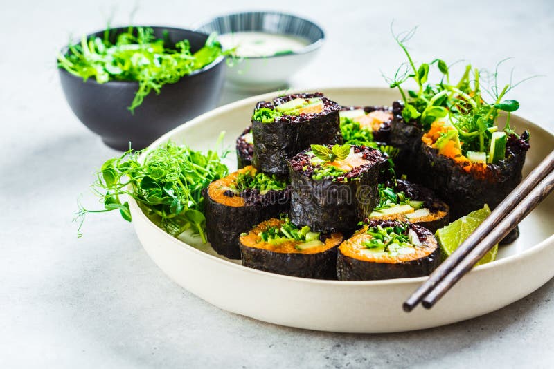 Vegan sushi rolls with black rice, avocado and sweet potato on white dish. Vegan food concept
