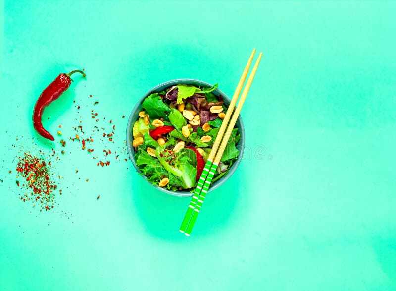 Vegan Vegetable Salad with Peanuts in blue bowl with chopsticks on green background. Organic food concept. royalty free stock image Vegan Vegetable Salad with Peanuts in blue bowl with chopsticks on green background. Organic food concept. royalty free stock image